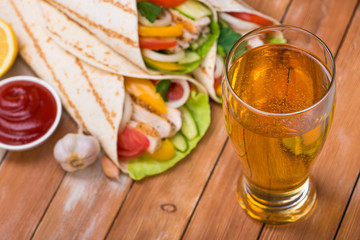 Tortilla wraps with grilled chicken and fresh vegetables and glass of beer