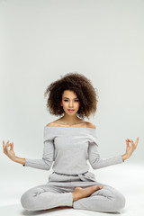 Young black woman practicing meditation isolated on grey background