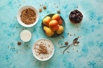 Two plates of muesli on a blue table. Muesli with dates and pears.