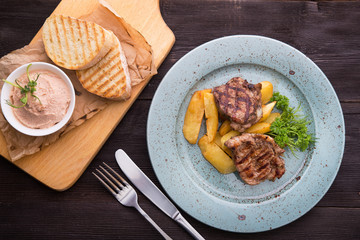 Tasty steak with potatoes on a blue plate