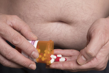 Man with overweight takes medication, conceptual image