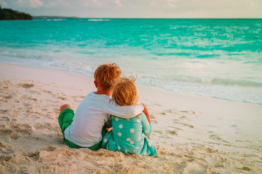 little boy and girl hug on beach vacation