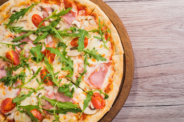 Fresh pizza with prosciutto meat, tomato and green arugula