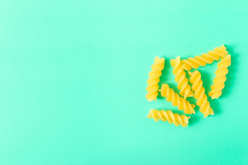 Uncooked fusilli pasta . Isolated on turquoise background