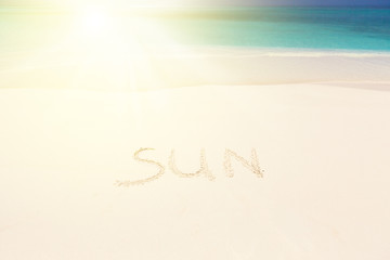 Handwritting inscription word SUN on sandy beach