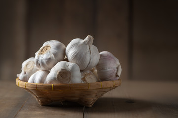 Garlic on bamboo basket on wood