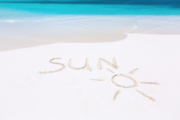 Handwritting inscription word SUN on sandy beach