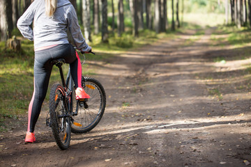 Naklejka premium Woman riding a mountain bicycle along path at the forest