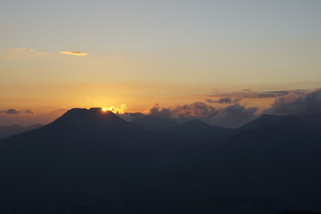 Obraz premium Krajobraz sylwetek góry przy wschodem słońca z pomarańczowymi niebami.