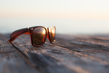 Brown sunglasses on a wooden table outdoors in the sunlight
