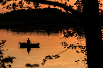 view of the lake with an angler on the boat at sunset