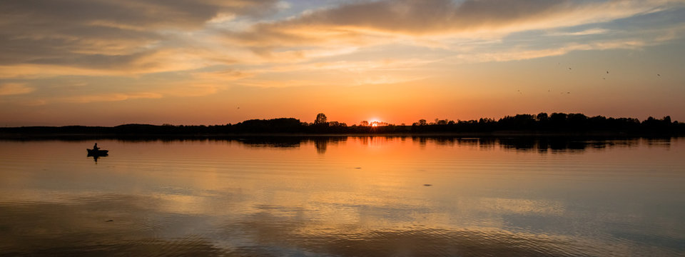 view of the lake with an angler on the boat at sunset