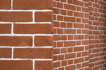 Red brick wall in perspective. Edge of brick wall. Geometric background image from angle of red brick.