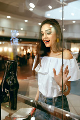Young Woman Looking Through Shop Window
