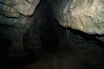 Beautiful cave. View from inside dark dungeon. Textured walls of cave. Background image of underground tunnel. Dampness inside cave. Light at end of tunnel.