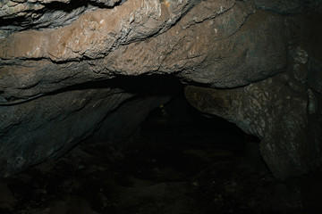 Beautiful cave. View from inside dark dungeon. Textured walls of cave. Background image of underground tunnel. Dampness inside cave. Lighting inside cave for excursions.