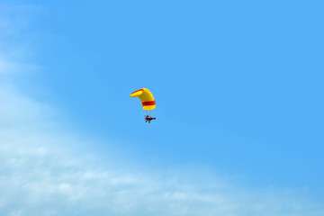 Paraglider flying in blue sky.