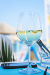 Refreshing glass of cold wine on a table in a stylish cafe on the beach. 
