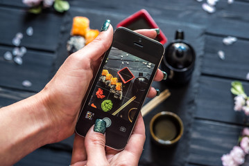 girl takes pictures of sushi on phone