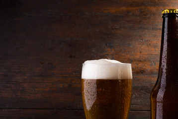 bottle and glass with beer on wood table