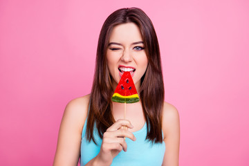It's better to lick it! Close up portrait of beautiful stylish trendy sexy attractive colorful funny joyful funky fancy girl wearing blue singlet biting lollipop on stick, isolated on pink background
