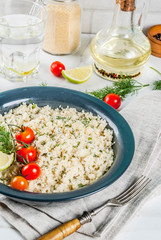 Light dietary food, couscous with tomatoes, lime and fresh herbs in dark bowl, white marble background