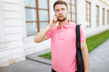 young handsome man walking around town and talking on the phone, hipster