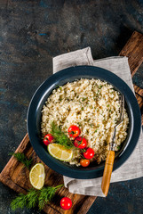 Light dietary food, couscous with tomatoes, lime and fresh herbs in dark bowl, dark blue background copy space