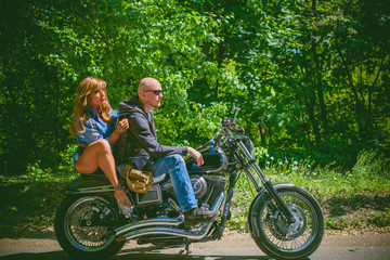 Obraz premium Middle age woman of athletic build, a bodybuilder athlete with a biker on a motorcycle having fun