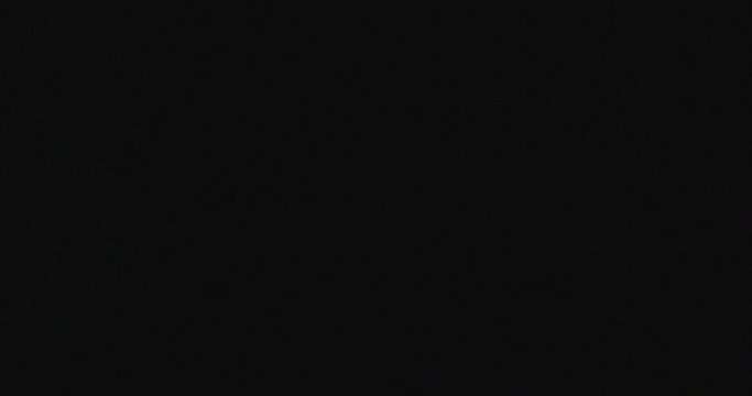 Man with beard lights the lighter in complete darkness outdoors