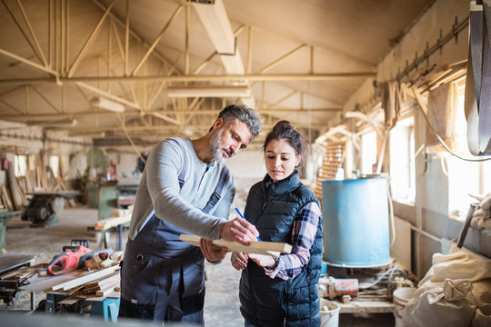 Man And Woman Workers In The Carpentry Workshop.