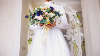 Attractive bride in white dress holding a bouquet of flowers
