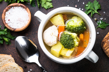 Chicken and vegetables soup on dark table. 