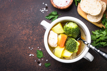 Chicken and vegetables soup on dark table. 