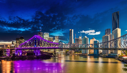 Naklejka na ściany i meble Vibrant night time and day time panorama of Brisbane city with purple lights on Story Bridge