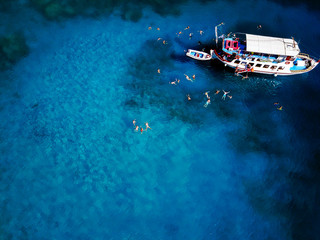 Aerial shot of beautiful blue lagoon at hot summer day with sailing boat. Top view of people are...