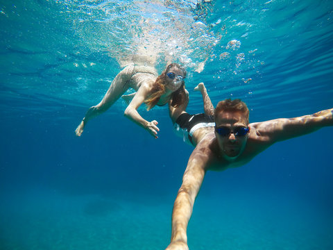 Cheerful couple having fun underwater and making selfie.