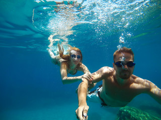 Cheerful couple having fun underwater and making selfie.
