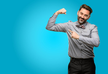 Middle age man, with beard and bow tie pointing biceps expressing strength and gym concept, healthy life its good