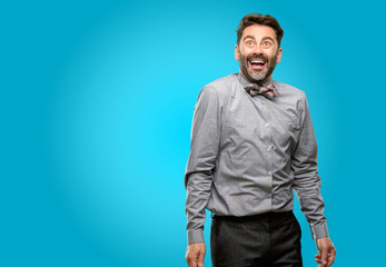 Middle age man, with beard and bow tie happy and surprised cheering expressing wow gesture
