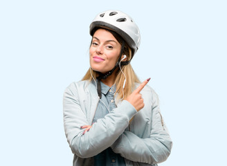 Young woman with bike helmet and earphones pointing away side with finger