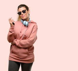 Young sport woman with headphones and sunglasses happy and surprised cheering expressing wow gesture