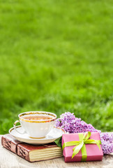 White cup with tea, flowers and gift box. Tea in the garden. Copy space