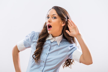 Image of beautiful businesswoman listening something on gray background.