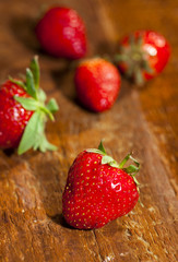 Fresh juicy strawberries with leaves on wooden background.