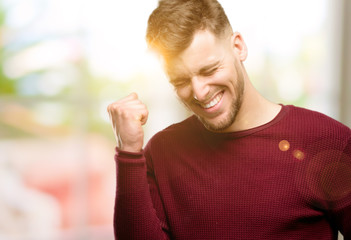 Handsome young man happy and excited celebrating victory expressing big success, power, energy and positive emotions. Celebrates new job joyful