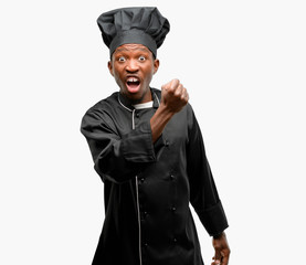 Young black cook wearing chef hat irritated and angry expressing negative emotion, annoyed with...