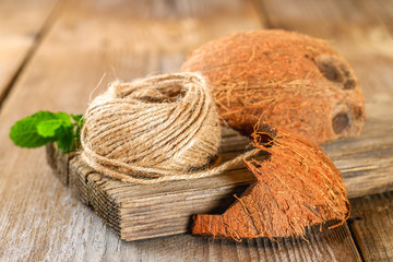 Rope of fiber coir and coconut shell on an old wooden table.