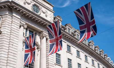 Close up of buildings on Regent Street London UK photographed from street level, with row of British flags to celebrate the Royal Wedding of Prince Harry to Meghan Markle.