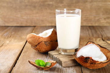 Coconut and coconut milk in glass, mint on wooden old table.